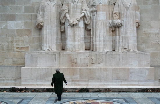 A man gazes up at the imposing statues of Genevan reformers on the Mur de la Reformation (1909-17). From left to right, they are: Guillaume Farel, the first to preach the Reformation in Geneva; John Calvin, leader of the Reformation movement and spiritual father of Geneva; Theodore Beza, Calvin's successor; and John Knox, a Scottish preacher, friend of Calvin, and founder of Scottish Presbyterianism.
